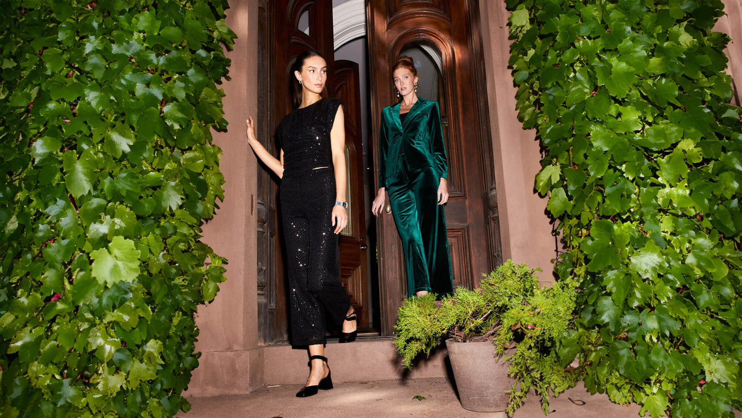 Two women leaving a building wearing NICOLE MILLER holiday outfits in green and black. 